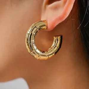 Close-up of a gold-colored bamboo-joint textured C-shaped hoop earring worn on the ear