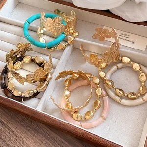 Collection of elegant three-piece metal flower bangle and beaded bracelet sets