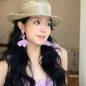 Detailed shot of pink chiffon flower earrings on a model for a beach vacation style