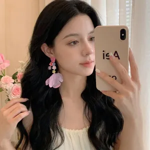 Detail of elegant chiffon petal drop earrings with colorful resin flowers on model