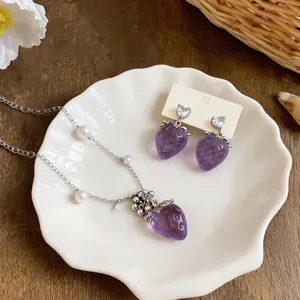 Vista dettagliata del set di gioielli a fragola viola con perle e zirconi a cuore.