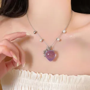 Primo piano di collana con ciondolo a fragola viola e accenti di perle sul collo