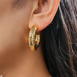 Close-up detail showing a gold bamboo textured C-shaped hoop earring worn on the ear