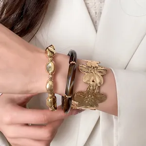 Detailed close-up showing a three-piece gold flower and tortoiseshell beaded bracelet set