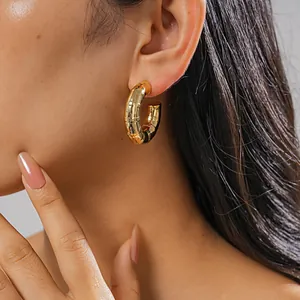 Detailed view of a gold bamboo-textured C-shaped hoop earring worn by a model