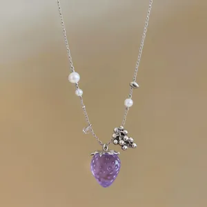 Vista dettagliata della collana con ciondolo fragola viola, perle e catena d'argento