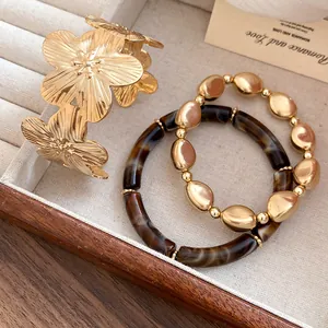 Detailed view of a 3-piece jewelry set with gold flower cuff and beaded bracelets