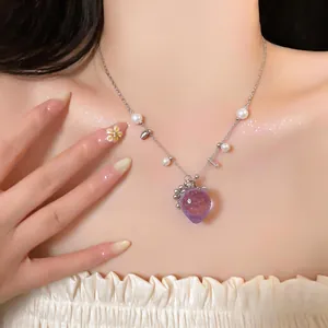 Dettaglio ravvicinato di una collana con ciondolo fragola viola e perle sul modello