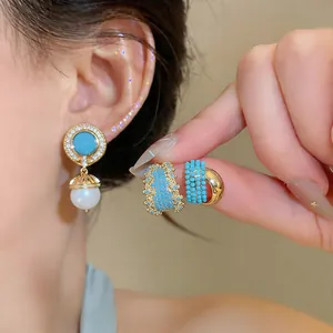 Close-up detail of vintage style turquoise and pearl drop earrings on a model's ear