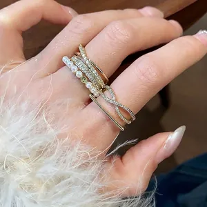 Anelli a strati placcati in oro 14k con perle bianche e zirconi lucenti sulla mano