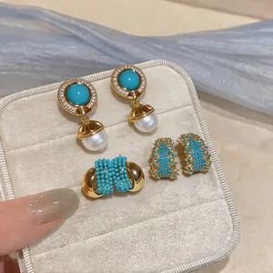 Close-up of vintage jewelry set with turquoise, pearls, and zircon earrings in a gift box.