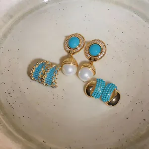 Close-up detail of elegant vintage gold earrings with turquoise stones and pearls