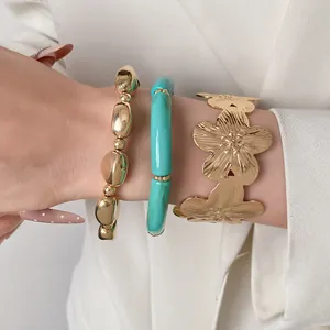 Detailed view of luxury gold flower cuff bangle and teal beaded bracelet set