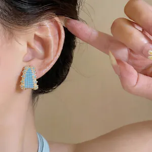 Detailed view of vintage geometric stud earrings with turquoise beads and zircon gold finish.