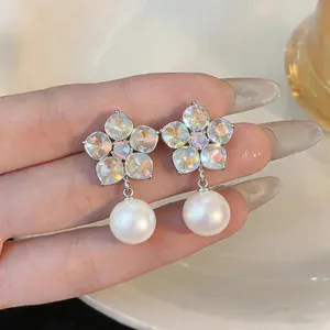 Detailed macro view of elegant flower earrings featuring iridescent crystals and white pearls.