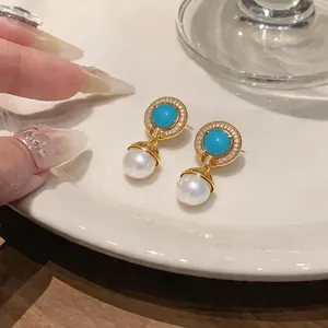 Detailed close-up of vintage gold earrings featuring turquoise blue stones and pearls