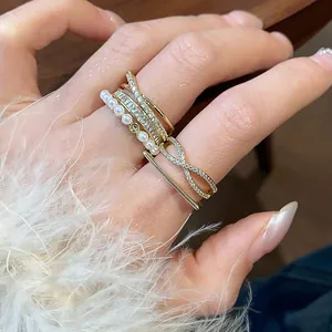 Dettaglio ravvicinato di anelli a fascia placcati in oro 14k con zirconi e perle sulla mano