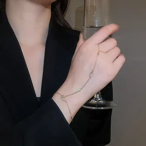 Close-up macro view of an elegant gold-tone zircon oval link slave bracelet worn on a hand
