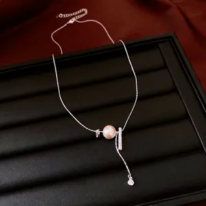 Elegant silver necklace with a pearl and pleated metal accents on a black tray