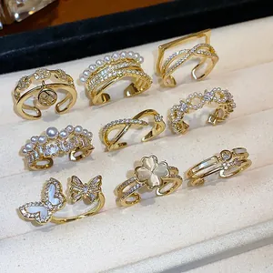Collezione dettagliata di anelli con perle e zirconi placcati oro 14k in un vassoio per gioielli