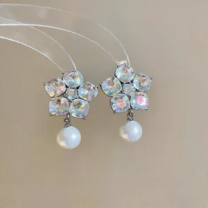 Detailed view of silver stud earrings featuring crystal flowers and elegant white pearl drops