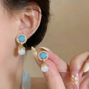 Detailed close-up of vintage geometric earrings with blue stones, zircons, and pearls.