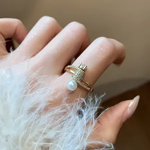Primo piano di un elegante anello dorato con pavé di zirconi e dettaglio di perla bianca