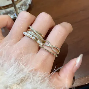 Dettaglio ravvicinato di anelli placcati in oro 14k con zirconi e perle sul dito.