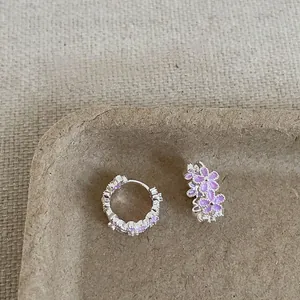 Primer plano de pendientes de aro plateados con flores púrpuras y piedras de circonitas