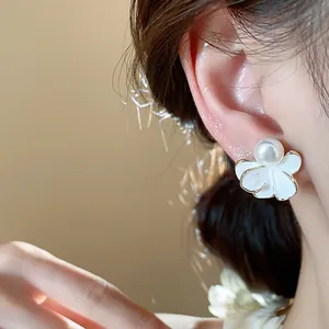 Detailed close-up view of an elegant 18k gold plated flower pearl earring on an ear