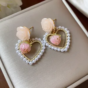 Close-up of 14k gold plated heart earrings with pearls, flowers and strawberry charms.