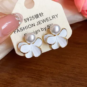 Close-up of white flower pearl stud earrings with 18k gold plating on display card