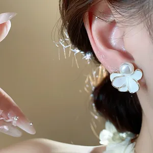 Detailed close-up showing a white flower pearl earring with 18k gold plating worn on an ear