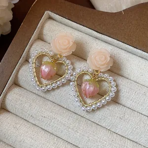 Close-up detail of romantic 14k gold plated flower heart earrings with pearls and strawberries