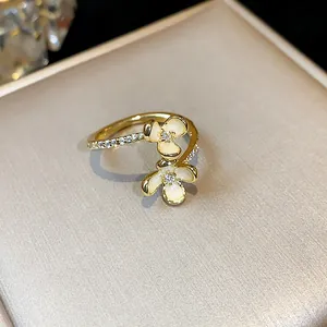 Dettaglio macro di anello placcato oro 14k con petali di fiori in smalto e zircone