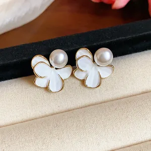 Close-up of 18k gold plated flower earrings with elegant white pearls and enamel details