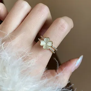 Primo piano di un anello a quadrifoglio placcato oro 14k con zirconi su un dito