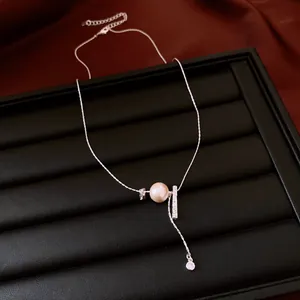 Detail view of dainty silver necklace with cream pearl and textured metallic bar pendant
