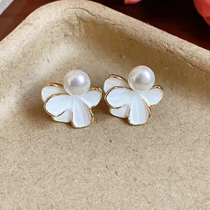 Close-up detail of 18k real gold plated flower stud earrings featuring white petals and center pearl