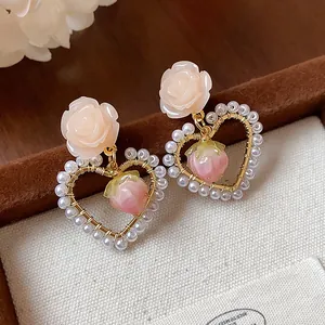 Detail macro view of 14k gold plated heart earrings with elegant rose and pearl accents