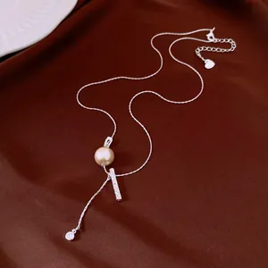 Close-up of a silver necklace with a pearl bead and a textured pleated bar pendant detail