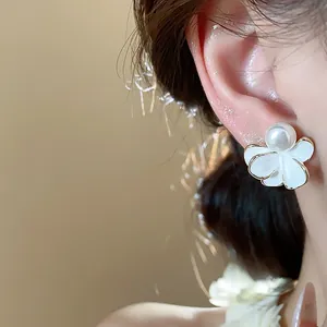 Elegant close-up view of a white flower pearl earring worn on the ear for detail