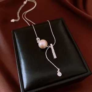 Detail of silver necklace with large pearl and textured metal bar on jewelry box