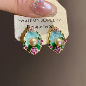 Primo piano dettagliato di orecchini vintage in smalto con elegante perla centrale