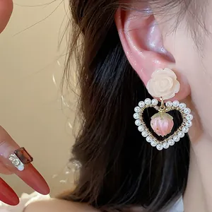 Detailed close-up of elegant rose and pearl heart drop earrings worn by an Asian model