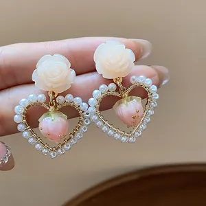 Close-up detail of 14k gold plated heart earrings with pearls and resin strawberries