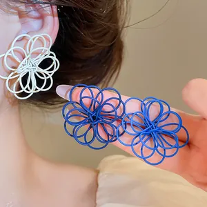 Detail view of large spray-painted wire flower stud earrings in blue and white