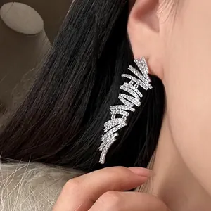 Gros plan d'une boucle d'oreille à pampilles géométriques en zircon brillant portée.