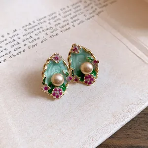 Dettaglio macro di orecchini vintage stile palazzo con fiori smaltati e perle