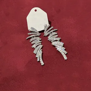 Gros plan d'élégantes boucles d'oreilles pompons géométriques plaquées or 18k et zircons.